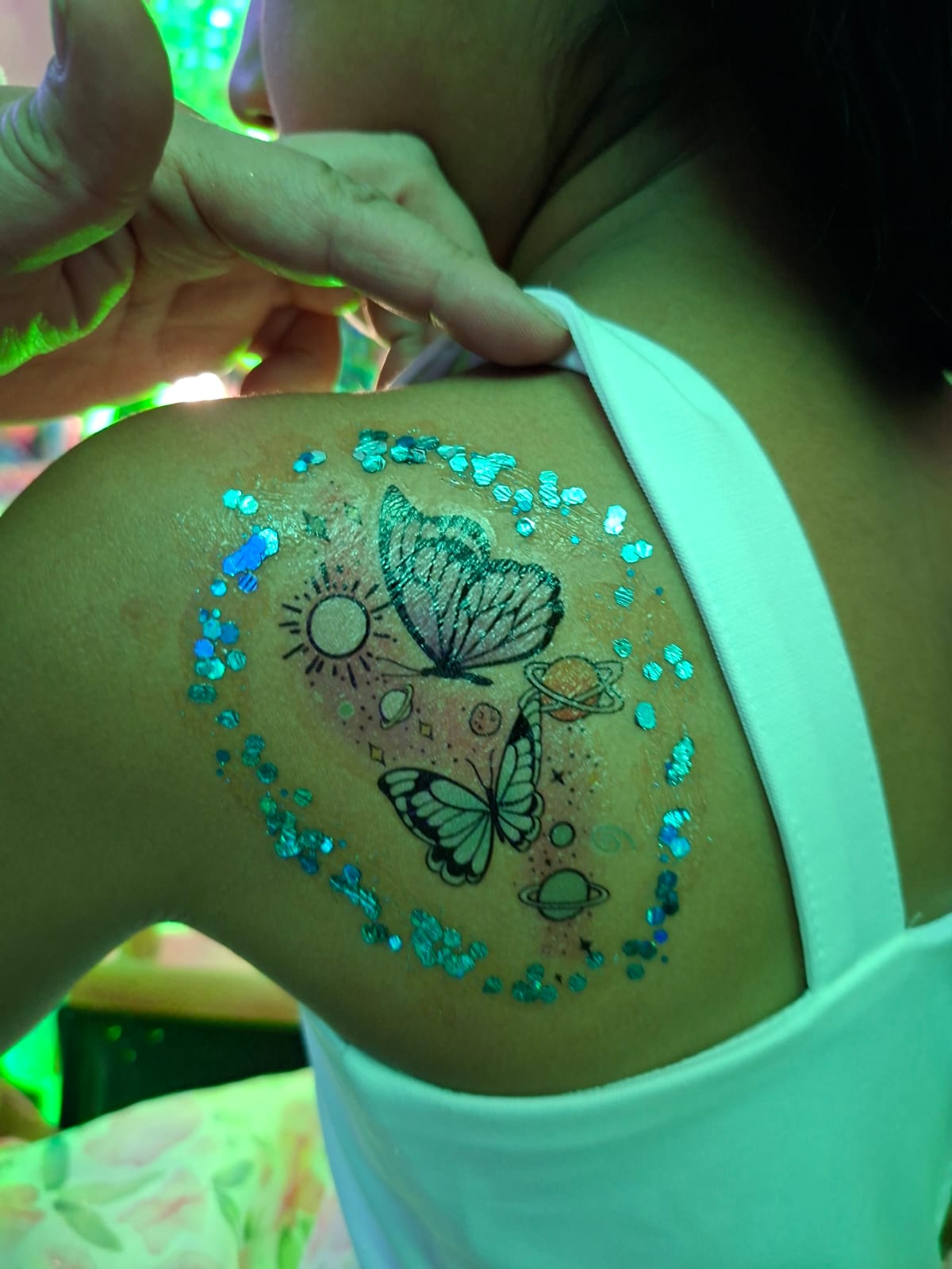 Detalle de pedrería y tatuaje temporal de mariposa